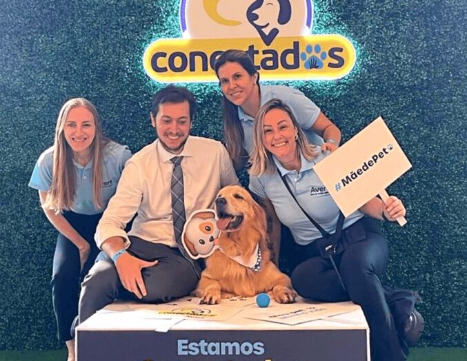 A photo of a group of people with a golden dog, where it stands on a platform with the words Estamo conectados, the logos of Biolab and Avert below. Above the group, the logo of the Conectados cause.