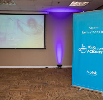 Banner with the Coffee with Shareholders event logo and in the background, a projection screen set up to show a presentation