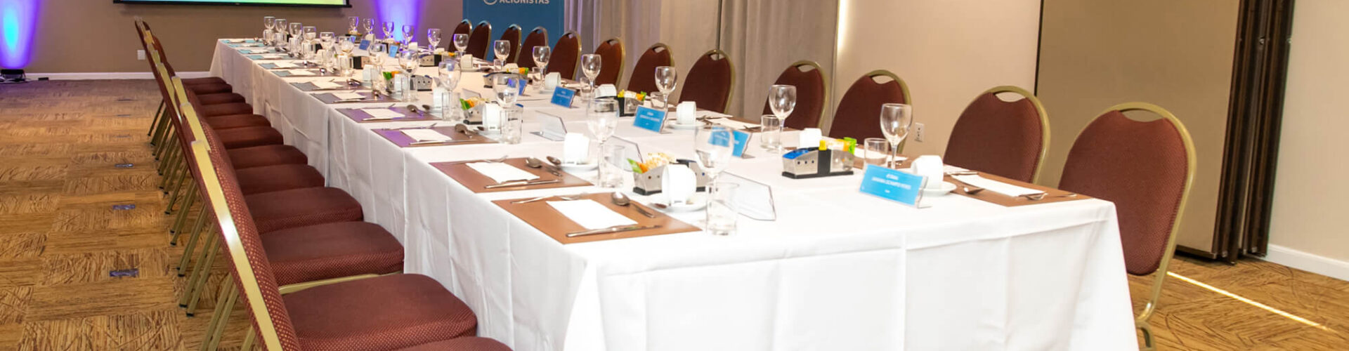 Photo of a meeting table set up to receive Biolab employees at the Coffee with Shareholders event, behind a projection screen set up to show a presentation.
