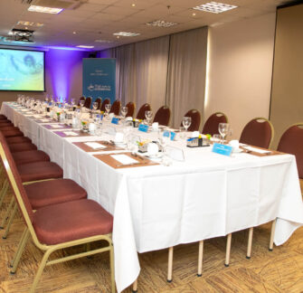 Photo of a meeting table set up to receive Biolab employees at the Coffee with Shareholders event, behind a projection screen set up to show a presentation.